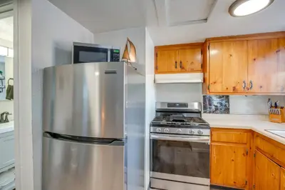 a stainless steel refrigerator in a kitchen with wooden cabinets at Walk to Beach Dog-Friendly Cabin in Glenbrook! in Glenbrook