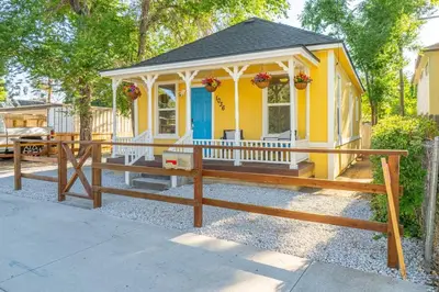 a small yellow house with a fence in front of it at Charming Family 2BR Midtown Reno - Pets Welcome in Reno