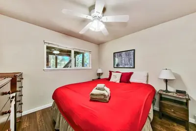 a bedroom with a red bed with a ceiling fan at Bear Haus - Sledding At Cabin - Forest Views - Foosball in South Lake Tahoe