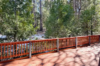 a wooden deck with a fence in the woods at Bearfoot Getaway in Shaver Lake