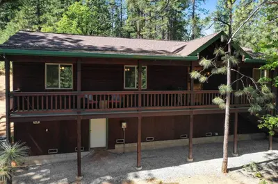 a house with a large deck in the woods at Great Cabin with AC Firepit Fireplace in Arnold