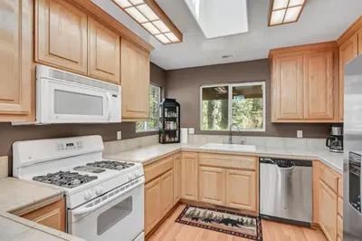 a kitchen with white appliances and wooden cabinets at Great Cabin with AC Firepit Fireplace in Arnold