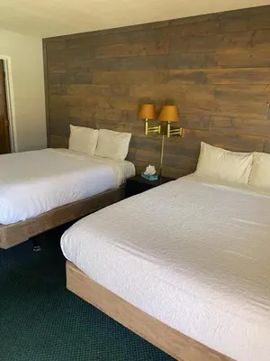 two beds in a hotel room with wooden walls at Whispering Pines in June Lake