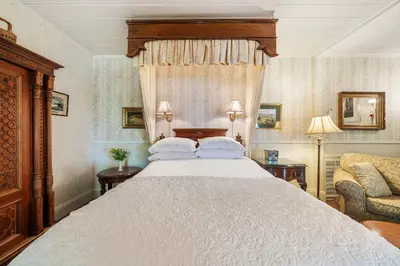 a bedroom with a large bed and a chair at Brinnwood Bed & Breakfast in Sutter Creek