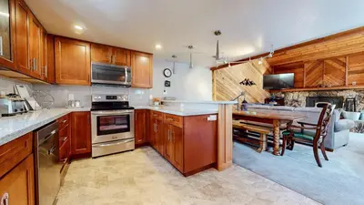 a kitchen with wooden cabinets and a dining room at Mammoth Sierra Townhomes #38 condo in Mammoth Lakes