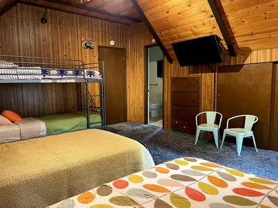a bedroom with two bunk beds and a flat screen tv at Groovy Cabin in the Woods in Pollock Pines