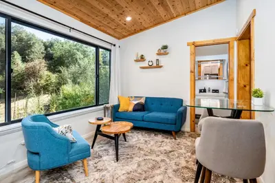 a living room with blue chairs and a glass table at Spacious Mountain View Oasis - Pool, Spa & Game Rm in Oakhurst