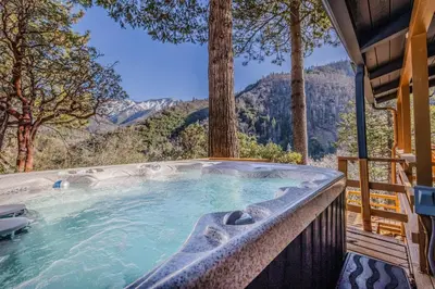 a hot tub with a view of the mountains at River Haus Sequoia | Hot Tub+New+King Beds+Views! in Springville