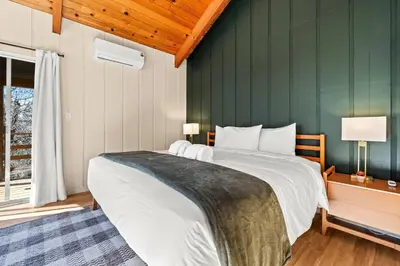 a bedroom with a large bed with a green wall at River Haus Sequoia | Hot Tub+New+King Beds+Views! in Springville