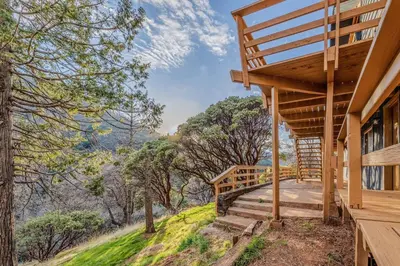 a wooden house with stairs leading up to a porch at River Haus Sequoia | Hot Tub+New+King Beds+Views! in Springville