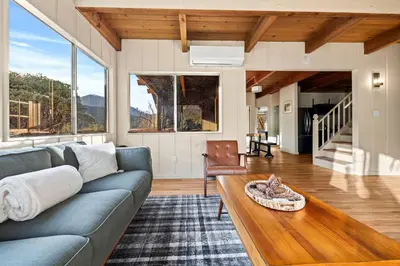 a living room with a couch and a table at River Haus Sequoia | Hot Tub+New+King Beds+Views! in Springville