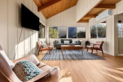 a living room with a couch and a tv at River Haus Sequoia | Hot Tub+New+King Beds+Views! in Springville
