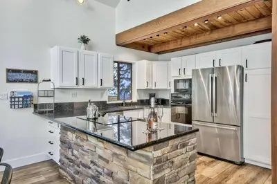 a kitchen with white cabinets and a stainless steel refrigerator at Cozy Cabin&HotTub Mins to N StarSki Sleeps 12 in Tahoe Vista