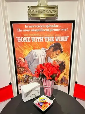 a movie poster on a wall with a table with flowers at Reno MidTown Movie House in Reno