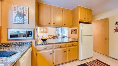 a kitchen with wooden cabinets and a white refrigerator at Mountain Cabin w Fireplace Balcony Easy Ski Access Bear Americana in Truckee