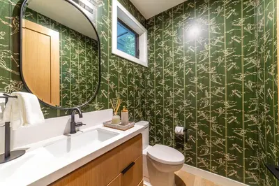 a bathroom with green wallpaper with a sink and a mirror at Spectacular New 4BR Townhome: Garage, Jacuzzi, BBQ in Mammoth Lakes