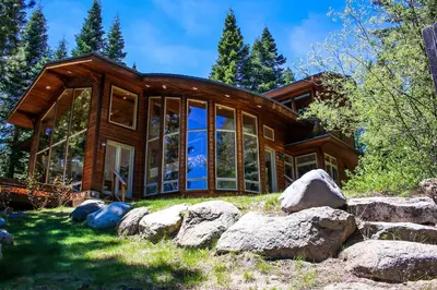 a large wooden house with large glass windows at Rubicon Bay Lakefront by Tahoe Getaways - 4BR with Bonus Room, Private Pier, Buoy & Beach Access in Tahoma