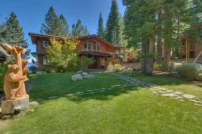 a house with a yard with a statue in front of it at Rubicon Bay Lakefront by Tahoe Getaways - 4BR with Bonus Room, Private Pier, Buoy & Beach Access in Tahoma