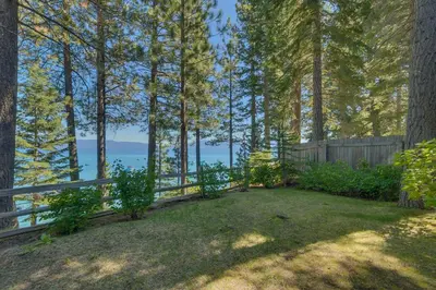 a backyard with a fence and a view of the water at Rubicon Bay Lakefront by Tahoe Getaways - 4BR with Bonus Room, Private Pier, Buoy & Beach Access in Tahoma