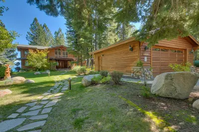 a home with a log cabin and a yard at Rubicon Bay Lakefront by Tahoe Getaways - 4BR with Bonus Room, Private Pier, Buoy & Beach Access in Tahoma