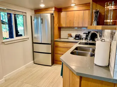 a kitchen with a stainless steel refrigerator and a sink at King Bed-Peaceful Modern Cottage-Garden Setting in Carmichael