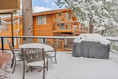 a deck with a table and chairs in front of a log cabin at Luxury Truckee Retreat with Hot Tub and Sauna in Truckee