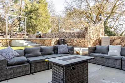 a patio with couches and a table and a stone wall at The Grand Waterside Estate Easy drive to Yosemite in Modesto