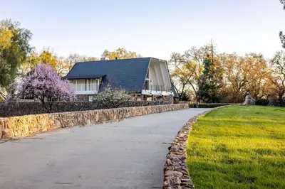 a house with a stone wall next to a driveway at The Grand Waterside Estate Easy drive to Yosemite in Modesto