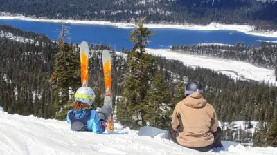 a man and a child sitting in the snow with snowboards at Blue Basecamp - Adventure Starts HERE! in Shaver Lake