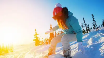 a woman riding a snowboard down a snow covered slope at Blue Basecamp - Adventure Starts HERE! in Shaver Lake