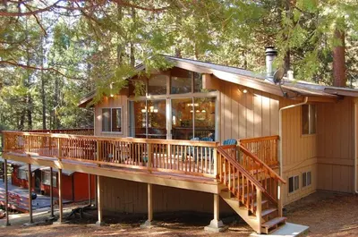 a house with a large deck in the woods at 10B Arrow Lodge in North Wawona