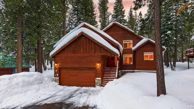 a cabin with snow on the roof in the woods at Pinewood Lodge by AvantStay Cozy Cabin Near Ski Resorts Hiking in Truckee