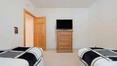 a bedroom with two beds and a television on a dresser at Pinewood Lodge by AvantStay Cozy Cabin Near Ski Resorts Hiking in Truckee