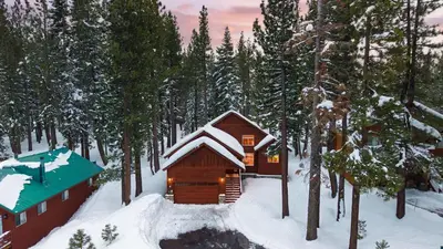 a cabin in the woods in the snow at Pinewood Lodge by AvantStay Cozy Cabin Near Ski Resorts Hiking in Truckee