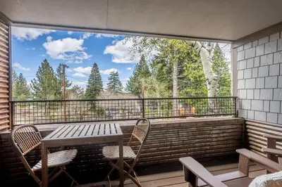 a balcony with a table and chairs and a large window at Cedar and Snow in Mammoth Lakes