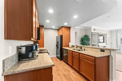 a kitchen with wooden cabinets and a black refrigerator at New Upscale 1BR Stay with Mini Golf Sauna & Heated Pool in Reno
