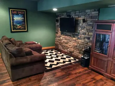 a living room with a couch and a television at Family-Friendly Log Cabin Rental in California's Gold Country near Sacramento in Volcano