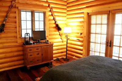 a bedroom with a bed and a lamp in a log cabin at Family-Friendly Log Cabin Rental in California's Gold Country near Sacramento in Volcano