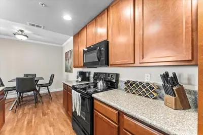 a kitchen with wooden cabinets and a black stove top oven at New Trendy 1BR Apartment with Heated Pool Gym & Minigolf in Reno