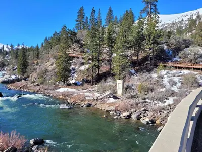 a bridge over a river next to a mountain at Newly remodeled mountain home! in Floriston