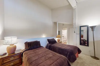 a bedroom with two beds and a table with a lamp at Summit 295 in Mammoth Lakes