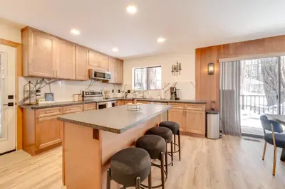 a kitchen with wooden cabinets and a large island with bar stools at Ski, Hike and Fish Cabin with Deck in Soda Springs! in Soda Springs