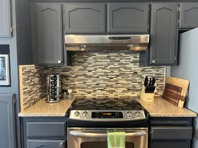 a kitchen with black cabinets and a stove top oven at Home at Yosemite Oakhurst in Oakhurst