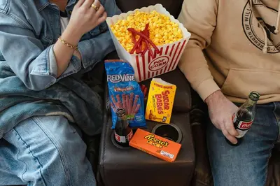 a man and woman sitting on a couch with popcorn and beer at My Side of the Mountain Rest Recharge Repeat in Shaver Lake