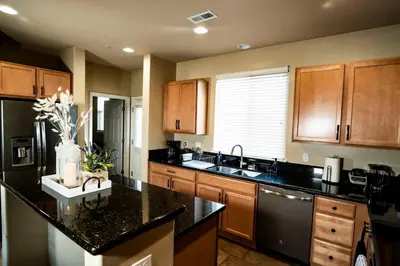 a kitchen with wooden cabinets and a black counter top at Eat-Sleep-Stroll-Repeat! Walkable Midtown 2BR Home in Reno