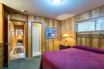 a bedroom with a purple bed and wooden walls at Yosemite's Riverfront Retreat in Wawona