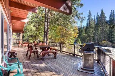 a deck with tables and chairs and a grill at Yosemite's Riverfront Retreat in Wawona