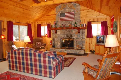a living room with a couch and a stone fireplace at 9N Fox Hollow in Wawona