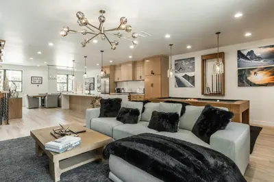 a living room and kitchen with a couch and a table at New Luxury 4BR /3BA Obsidian Reserve #110 – Hot Tub, 2-Car Garage, Pool Table, Mount Views! in Mammoth Lakes