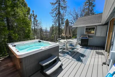 a hot tub on a deck next to a house at Near Yosemite Bass Lake Cabin with Hot Tub, Lake View, Pet Friendly in Bass Lake